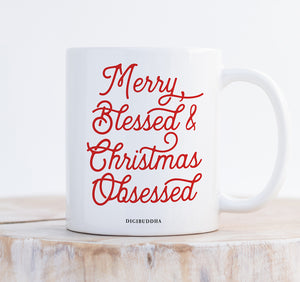 A white ceramic Christmas mug with Merry Blessed & Christmas Obsessed printed in red, festive script. Perfectly embodies the obsessed with Christmas spirit.
