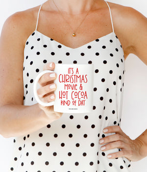 Red, playful and festive text "It's a Christmas movie & hot cocoa kind of day" on a white ceramic coffee mug by Digibuddha.