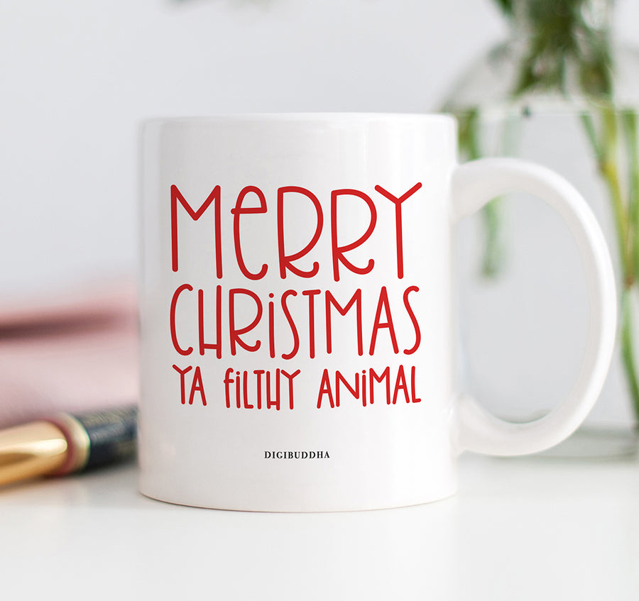 A white ceramic Christmas mug with Merry Christmas Ya Filthy Animal printed in a red, playful, trendy font. The perfect blend of holiday cheer and humor.
