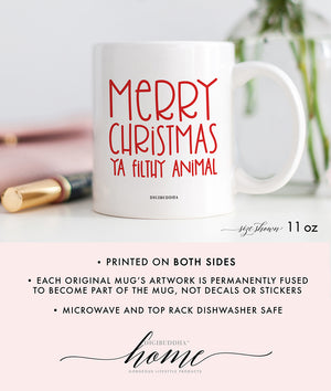 A white ceramic Christmas mug with Merry Christmas Ya Filthy Animal printed in a red, playful, trendy font. The perfect blend of holiday cheer and humor.