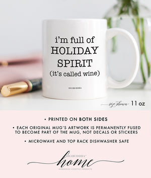 A white ceramic coffee mug with I'm Full of Holiday Spirit It's Called Wine printed in playful, modern font.